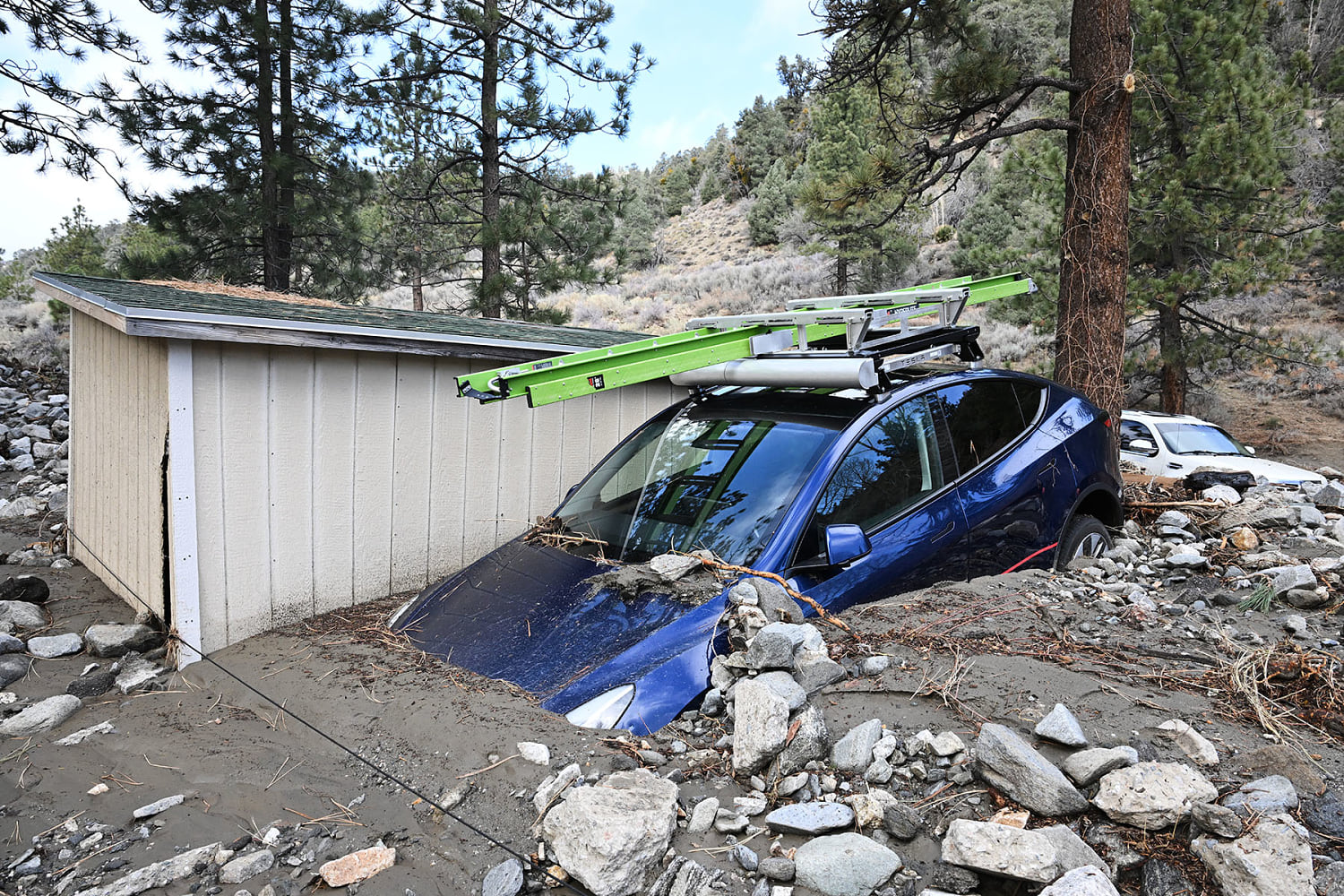 A car is buried in mud after a series of storms Thursday, Dec. 25, 2025, in Wrightwood, Calif.  (William Liang / AP)