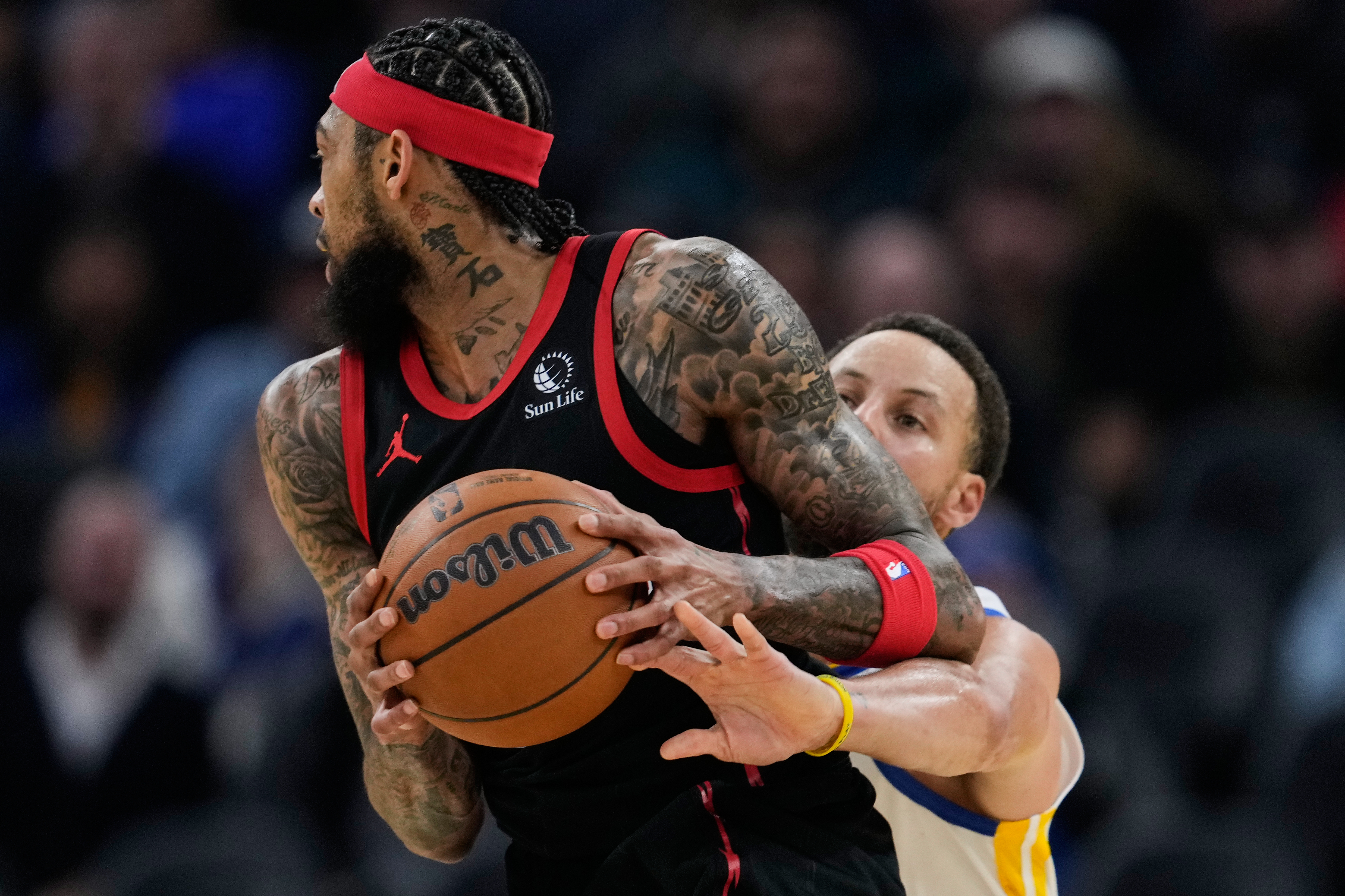 Golden State Warriors guard Stephen Curry, right, tries to knock the ball away from Toronto Raptors forward Brandon Ingram during the first half of an NBA basketball game, Tuesday, Jan. 20, 2026, in San Francisco. (AP Photo/Godofredo A. Vásquez)
