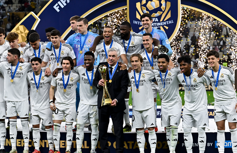 The men's Real Madrid team pose with the Intercontinental Cup trophy while wearing winners medals