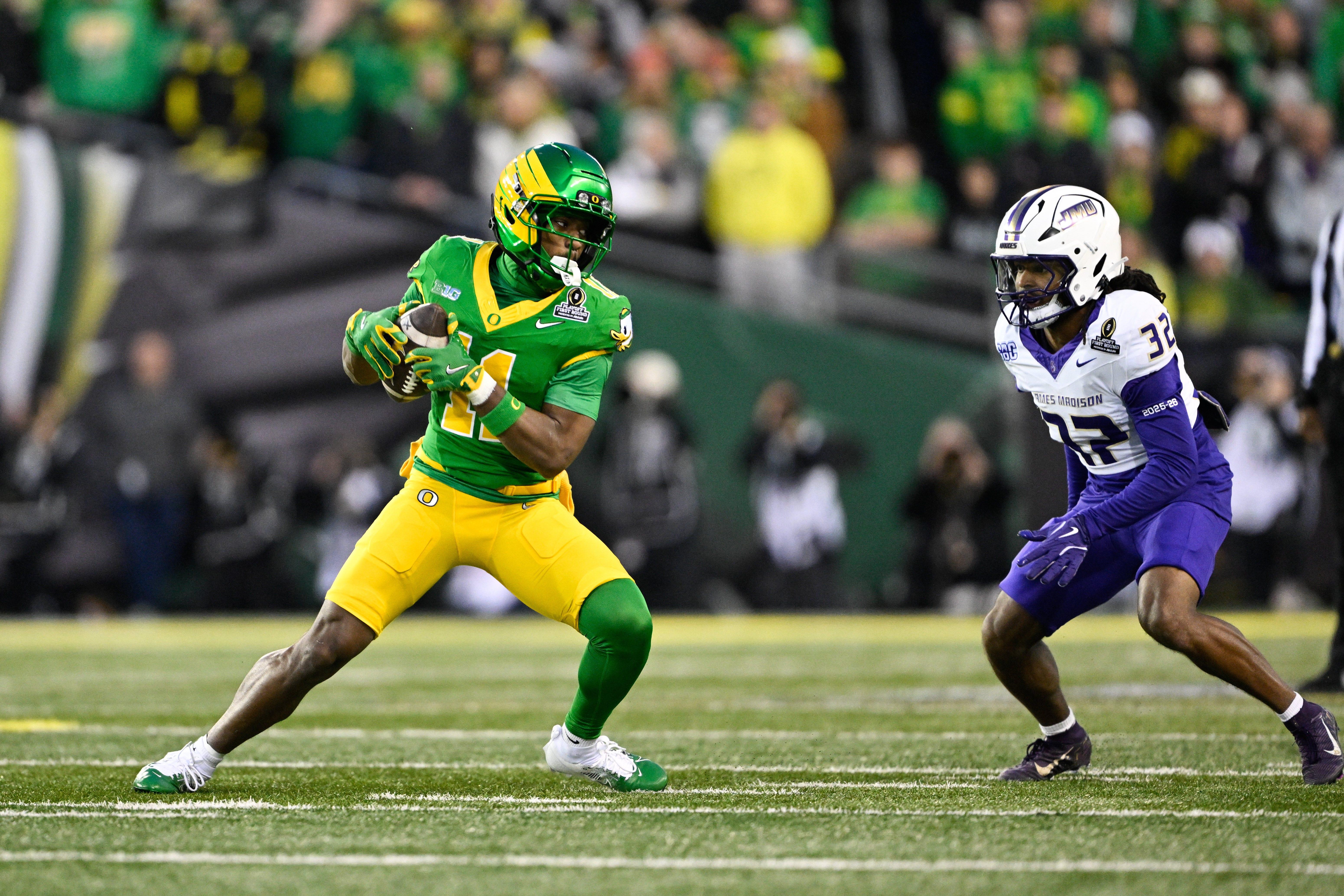 Dec 20, 2025; Eugene, OR, USA; Oregon Ducks wide receiver Jeremiah McClellan (11) runs after making a catch as James Madison Dukes defensive back DJ Barksdale (32) defends during the first quarter at Autzen Stadium. Mandatory Credit: Troy Wayrynen-Imagn Images