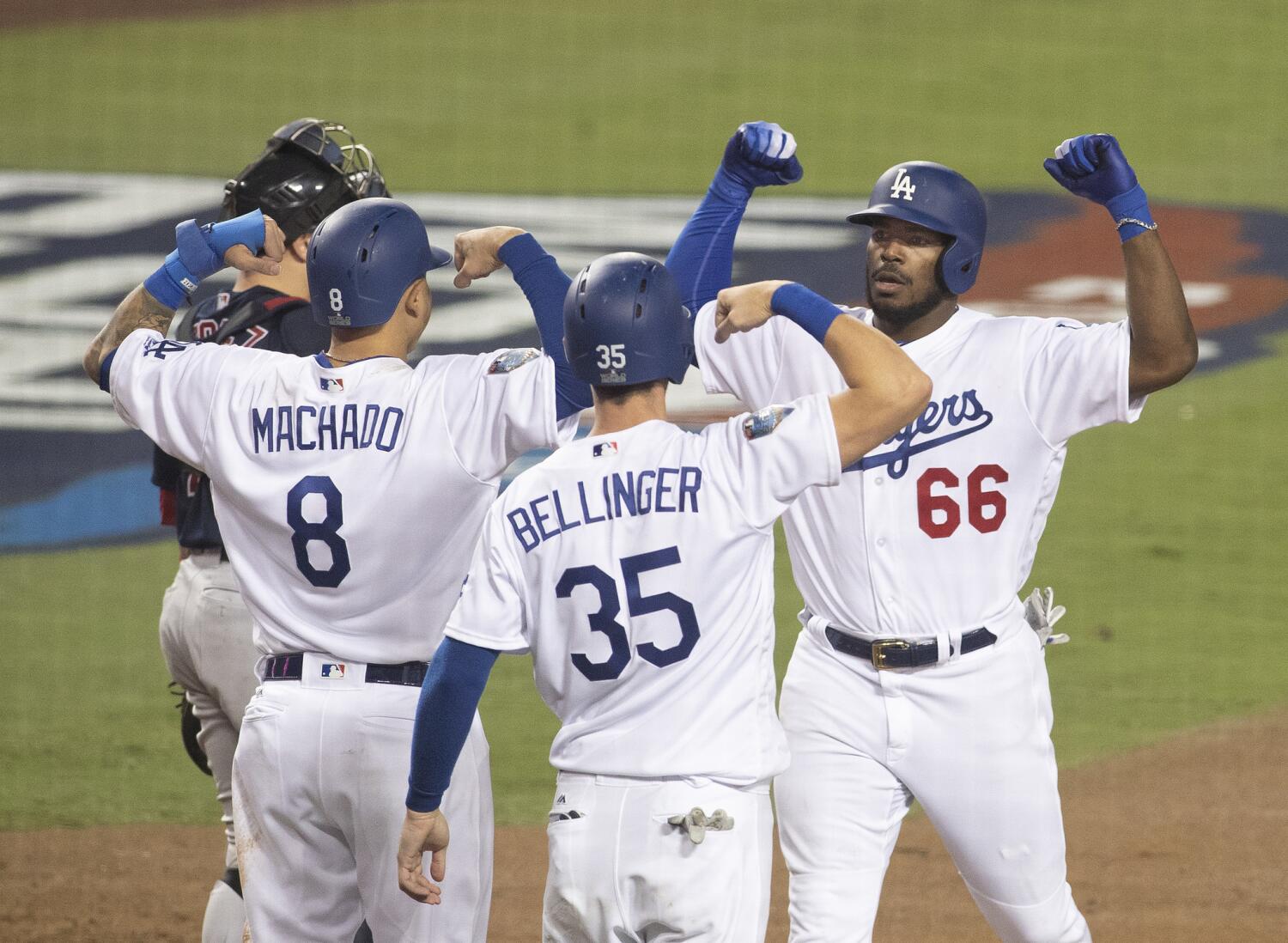 A group of baseball players wearing Dodgers uniforms celebrate by flexing their muscles