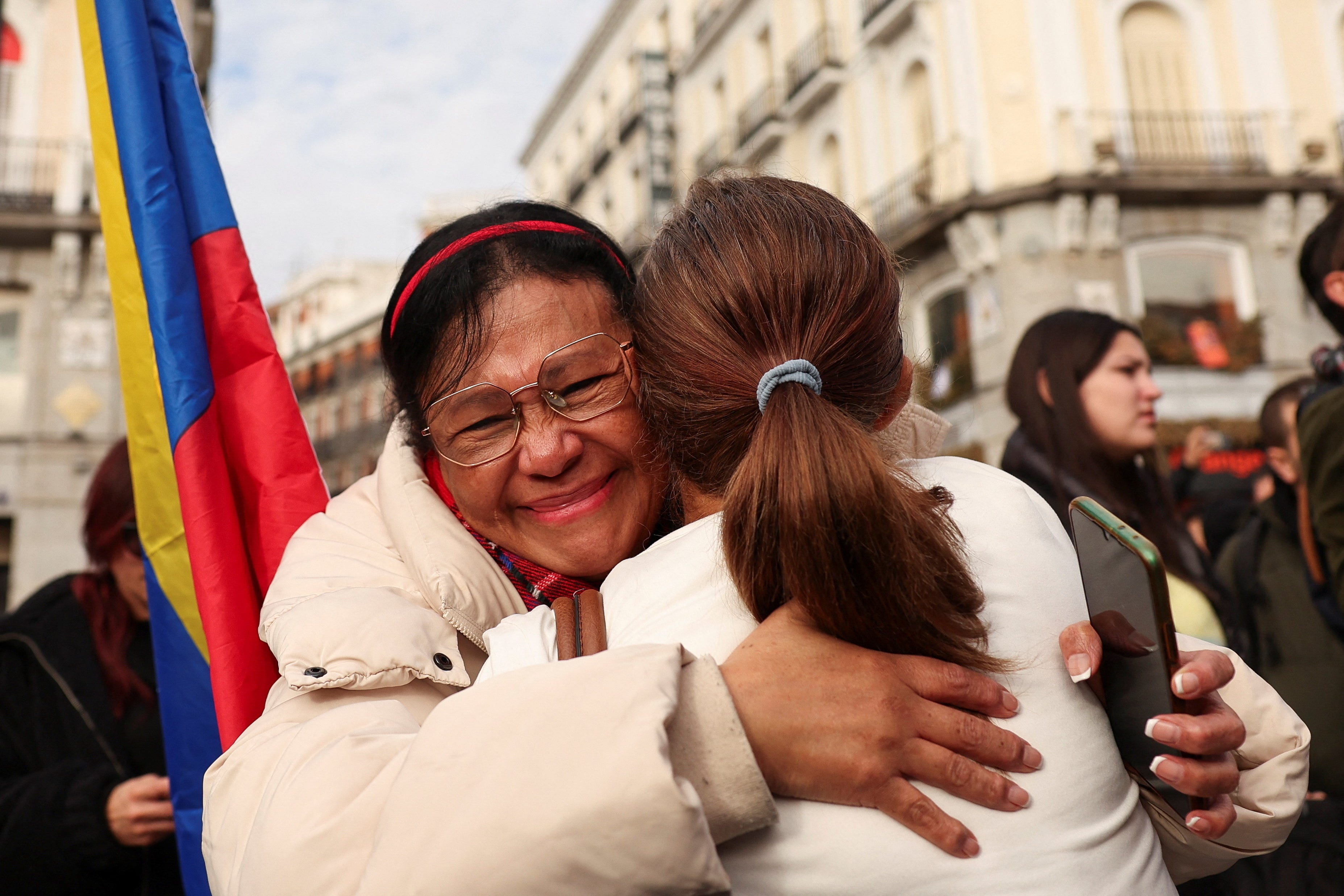 People embrace next to a Venezuelan flag, as they react to the news after U.S. President Donald Trump said the U.S. has struck Venezuela and captured its President Nicolas Maduro, in Madrid, Spain, January 3, 2026.