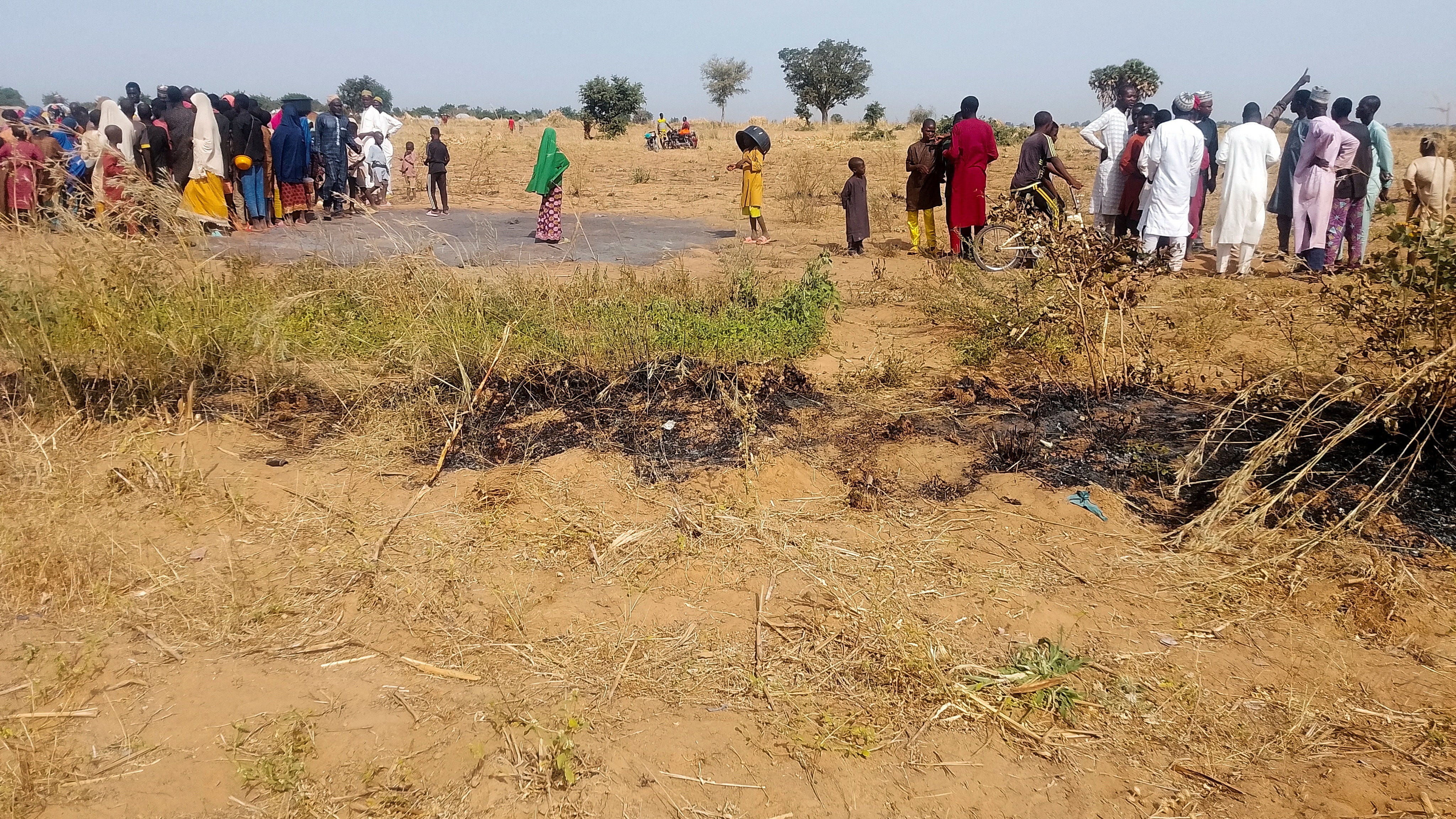 People gather at a site where burnt grass is seen in Jabo village, after U.S. forces had launched a strike against Islamic State militants in northwest Nigeria at the request of Nigeria's government, as U.S. President Donald Trump announced on Truth Social on December 25, in Sokoto state, Nigeria, December 26, 2025.